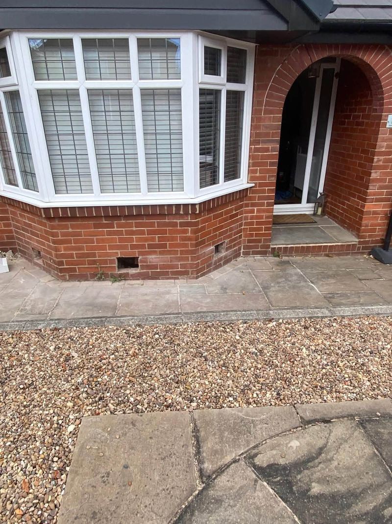 Front of a brick house with a bay window and old air bricks, before the work