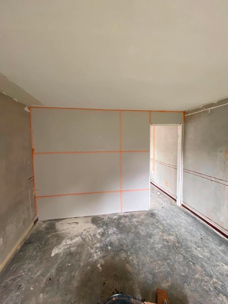 New stud wall boarded out across the room with a door opening