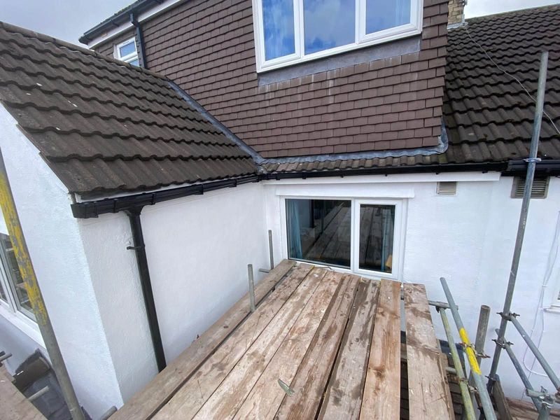 New black fascias and gutters on a rendered house with a dormer, seen from the scaffold