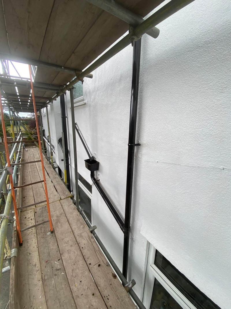 Run of new downpipes along a rendered wall from the scaffold