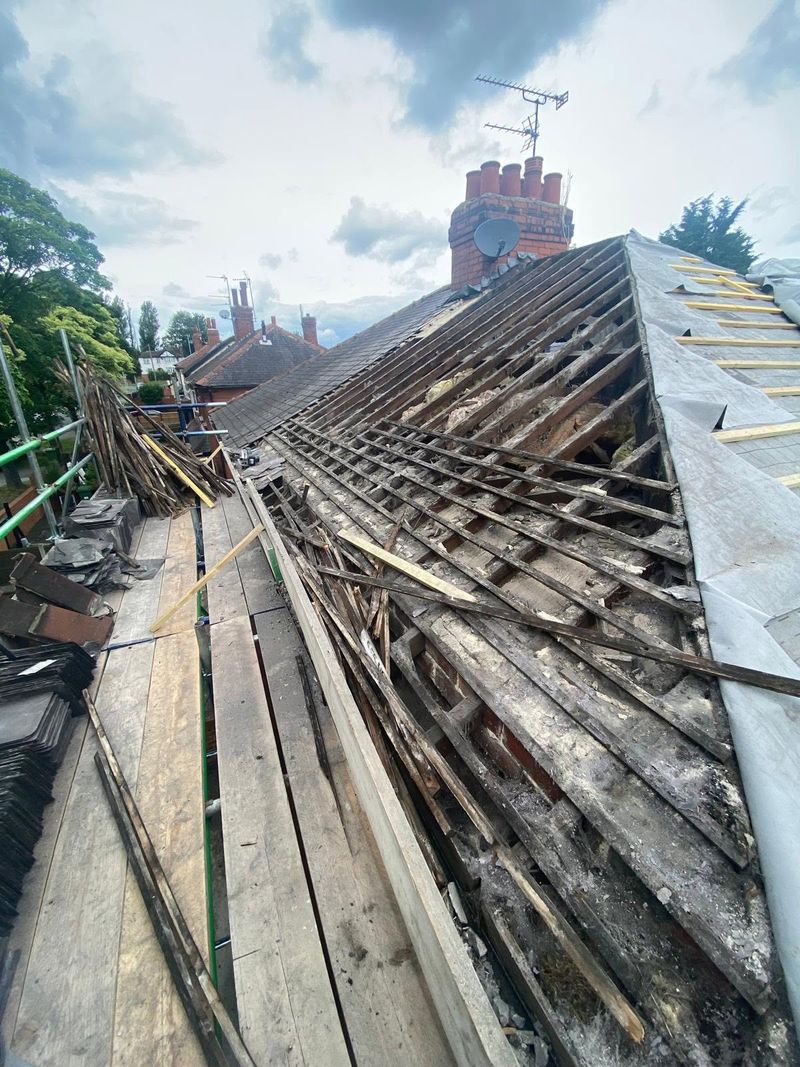 The old covering being stripped off, exposing the battens along the roof