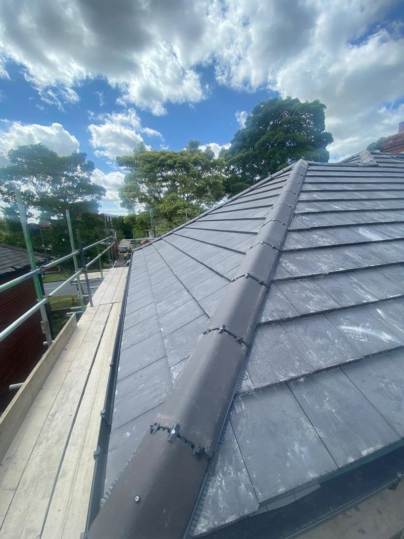 The new grey tiles laid up to the hip, seen along the finished roof