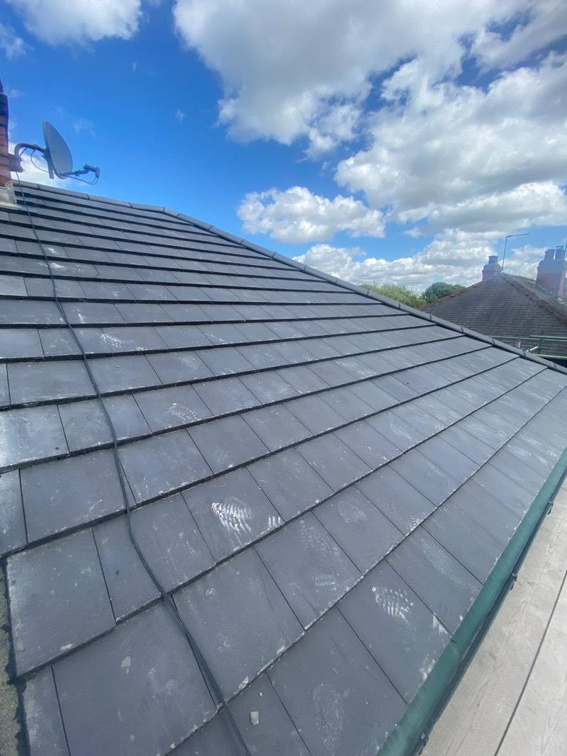 The completed roof in new grey tiles against a blue sky