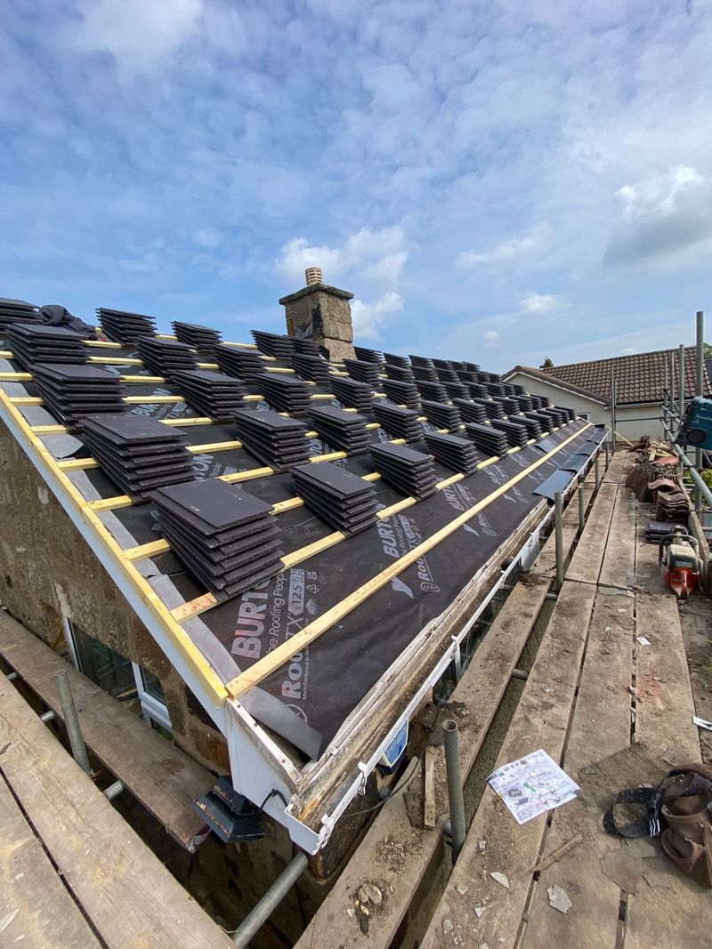 New grey tiles being laid in courses up the roof slope